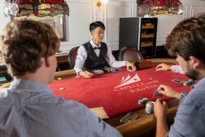 Un hombre sentado en una mesa de póquer con tres hombres. en Halong Lyra Grandeur Cruise, en Ha Long