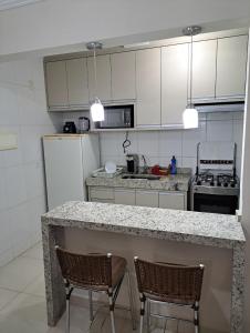 a kitchen with a counter and two chairs in it at Apto Completo, proximo ao Shopping in Taubaté