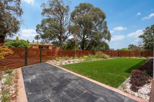 ein Garten mit Zaun und Rasen in der Unterkunft Spacious 5-Bed Family Home in Giralang in Ginninderra