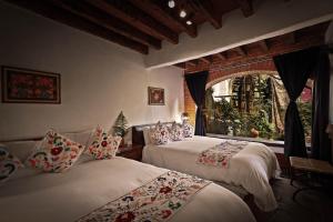 a bedroom with two beds and a window at Mesón De Leyendas Breakfast & Downtown in Valle de Bravo