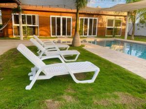 twee ligstoelen op het gras bij een zwembad bij Casa Doral Monterrico in Monterrico