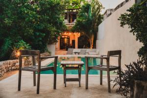 2 Stühle und ein Tisch vor einem Pool in der Unterkunft Casa De Cortes in Mérida