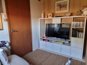 a living room with a television in a white entertainment center at Farmstay in Elingamite North