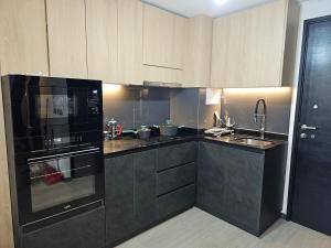 una cocina con electrodomésticos negros y armarios de madera en 2D apartment and 2 baths, 4 P, temperate pool, en Puerto Varas