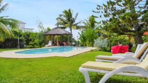 a yard with a swimming pool and two lounge chairs at Spacious villa with sea view in Trou D'Eau Douce in Trou dʼ Eau Douce