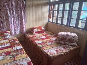 two twin beds in a room with windows at Hurenkey homestay in Gorkhe