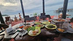 a table with plates of food on a table near the water at Ruenton Resort เรือนต้น รีสอร์ท in Bang Sare