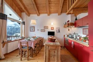 a kitchen with red cabinets and a table with chairs at Gleise Lodge apartment - Happy Rentals in Bardonecchia