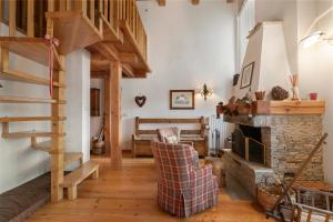 a living room with a staircase and a stone fireplace at Gleise Lodge apartment - Happy Rentals in Bardonecchia