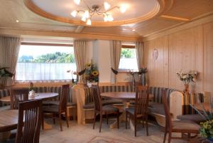 a restaurant with wooden tables and chairs and a ceiling at Agritur Maso Chemela in Cavalese