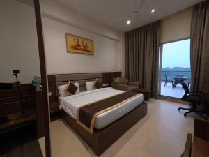a hotel room with a bed and a large window at Neelam Orchid in Kānpur +12 photos