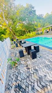 a stone patio with a picnic table next to a swimming pool at Suriya Cottage Family Resort in Habarana +16 photos