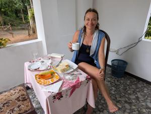 a woman sitting at a table with a cup of coffee at Jb Villa in Bona Vista