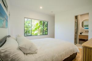 布德林姆Our Treehouse near Mooloolaba的白色卧室设有一张大床和窗户