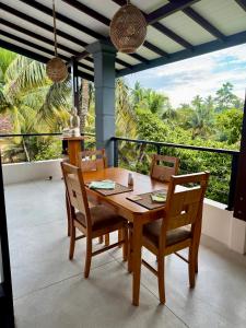 a dining room with a table and chairs and a balcony at Madiha Venus in Matara