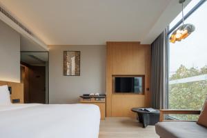 重庆The Boutique Hotel with Authentic Antique Collection & Suzhou Garden的一间带床、电视和窗户的卧室