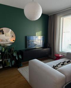 a living room with a white couch and a green wall at Cozy Top-Floor Studio in Turku - Near City Center in Turku