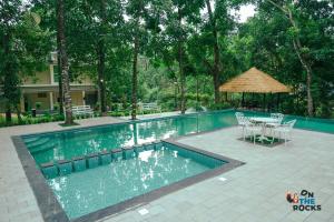 AthirappillyAthirapilly Ontherocks的游泳池旁配有桌椅