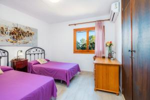 a room with two beds with purple sheets and a window at S' Alzina in Sencelles +26 photos