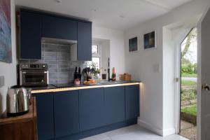 a kitchen with blue cabinets and a stove at Fairy Cottage in Lea