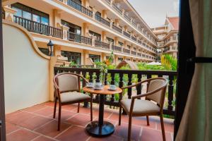 a balcony with two chairs and a table and a building at Bayon Era Hotel in Siem Reap