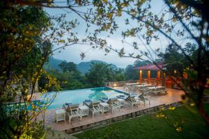 a pool with tables and chairs next to a building at Martam Village Resort in Gangtok +25 photos