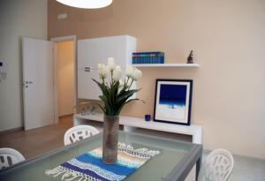 ein Esszimmer mit einem Glastisch mit einer Vase mit weißen Blumen in der Unterkunft Apartment Corso Cavour in Bari