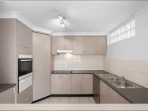 una cucina con mobili bianchi e un lavandino di A 3 bedders close to everything a Brisbane