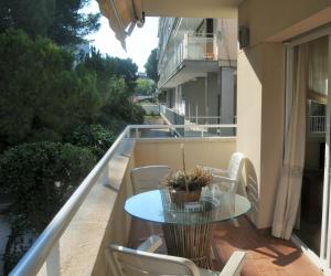balcón con mesa de cristal y sillas en Apartaments Villa Conchi, en Sitges