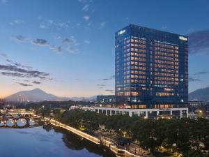 a tall building next to a river with a bridge at Hilton Yuyao in Yuyao