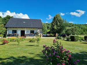a small white house with flowers in the yard at Apartment Rosandić in Smoljanac
