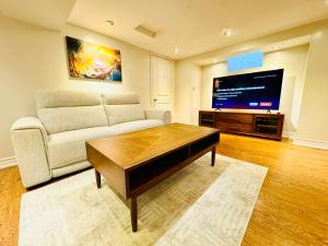 a living room with a couch and a flat screen tv at Spacious and Modern Family-Friendly 2-Bedroom Apartment - Near Airport & Toronto Downtown in Brampton