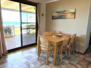 a dining room with a wooden table and chairs at Fareview Beach House in Emu Bay