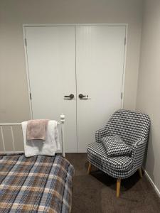 a bedroom with a bed and a chair and a closet at Love House in Auckland