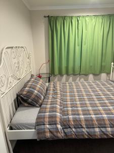 a bedroom with a bed with a green curtain at Love House in Auckland