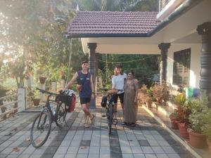 a group of people standing next to a house with their bikes at Munnar Village Homes in Munnar