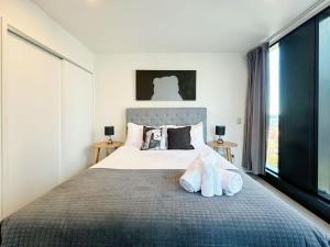 奥克兰Modern 2 Bedroom Beside Skytower & Queen St in The Heart of CBD的一间卧室配有一张大床,上面有两双鞋 更多16张照片