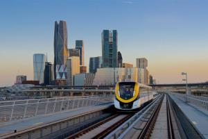 a yellow and white train on tracks in front of a city at Executives Hotel - KAFD in Riyadh
