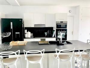 a kitchen with a black refrigerator and white cabinets at CANET PLAGE Maison avec terrasses in Canet-en-Roussillon