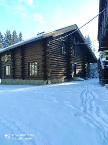 a log cabin with snow in front of it at Tatova Hata in Yablunytsya