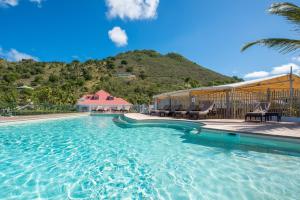 a swimming pool with chairs and a mountain in the background at Grand Case Beach Club in Grand Case