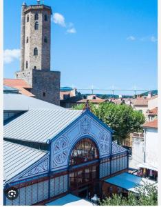 un bâtiment bleu avec une tour d'horloge dans une ville dans l'établissement Studio SO rez de chaussée centre-ville, à Millau