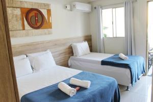 a hotel room with two beds with towels on them at Pousada Das Palmeiras in Jaboatão dos Guararapes