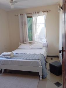 a bedroom with a large bed with a window at G-wel's Sun Sweet Apartment in Mombasa +6 photos