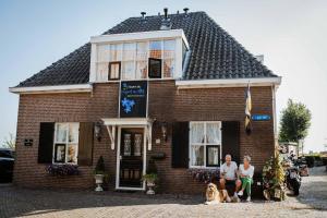 two people and a dog in front of a brick house at Overnachten bij Vergeet me Niet in Blokzijl in Blokzijl