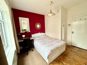 a bedroom with a red wall with a bed and a desk at Winton house home stay in Bournemouth