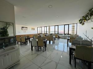 ein Esszimmer mit Tischen, Stühlen und Fenstern in der Unterkunft Toprak Hotel in Van