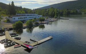 a building on a lake with boats in the water at Appart'Hôtel LIDO au bord de l'eau in Gérardmer