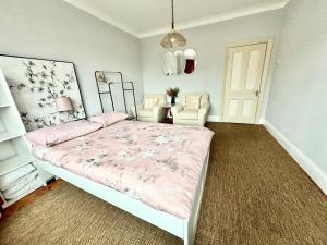 a bedroom with a pink bed and two chairs at Winton house home stay in Bournemouth