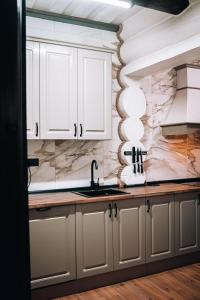 a kitchen with white cabinets and a sink at Tatova Hata in Yablunytsya +92 photos